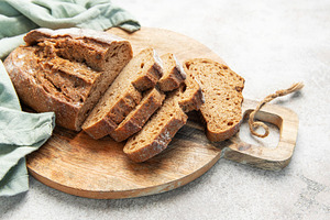 Slicing fresh whole grain rye bread on wooden board, a Food & Drink Photo by Olena Rudo