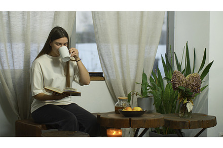 Young woman is reading book with tea, a Person Photo by Media Whale Stock