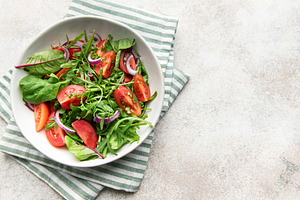 Bowl holding healthy green salad on striped napkin, a Food & Drink Photo by Olena Rudo