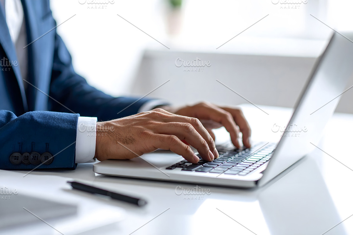Businessman in suit working on laptop at modern desk, a Business Photo by GoodGoods (Photo 2 of 2)