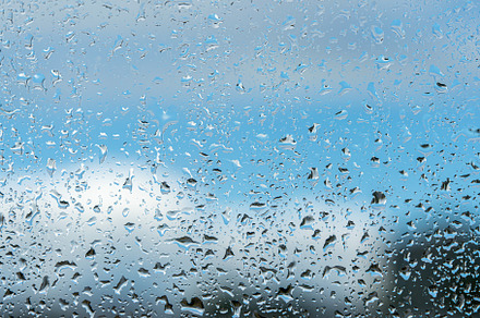 Raindrops on a window with a blue cloudy sky in the background., an Abstract Photo by Eugene_Photo