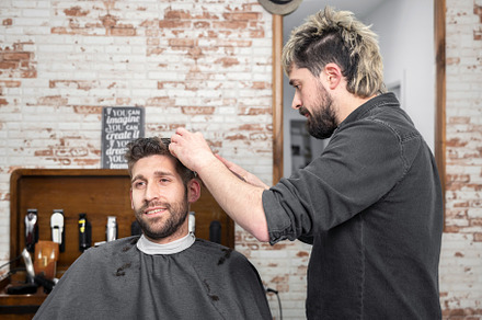 Man barber cutting hair of male client with clipper at barber shop. Hairstyling, a Person Photo by david.herraez.calzad