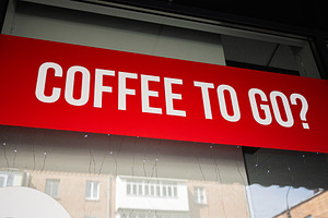 Bold red coffee to go sign with urban background in day time, a Photo by AS photostudio