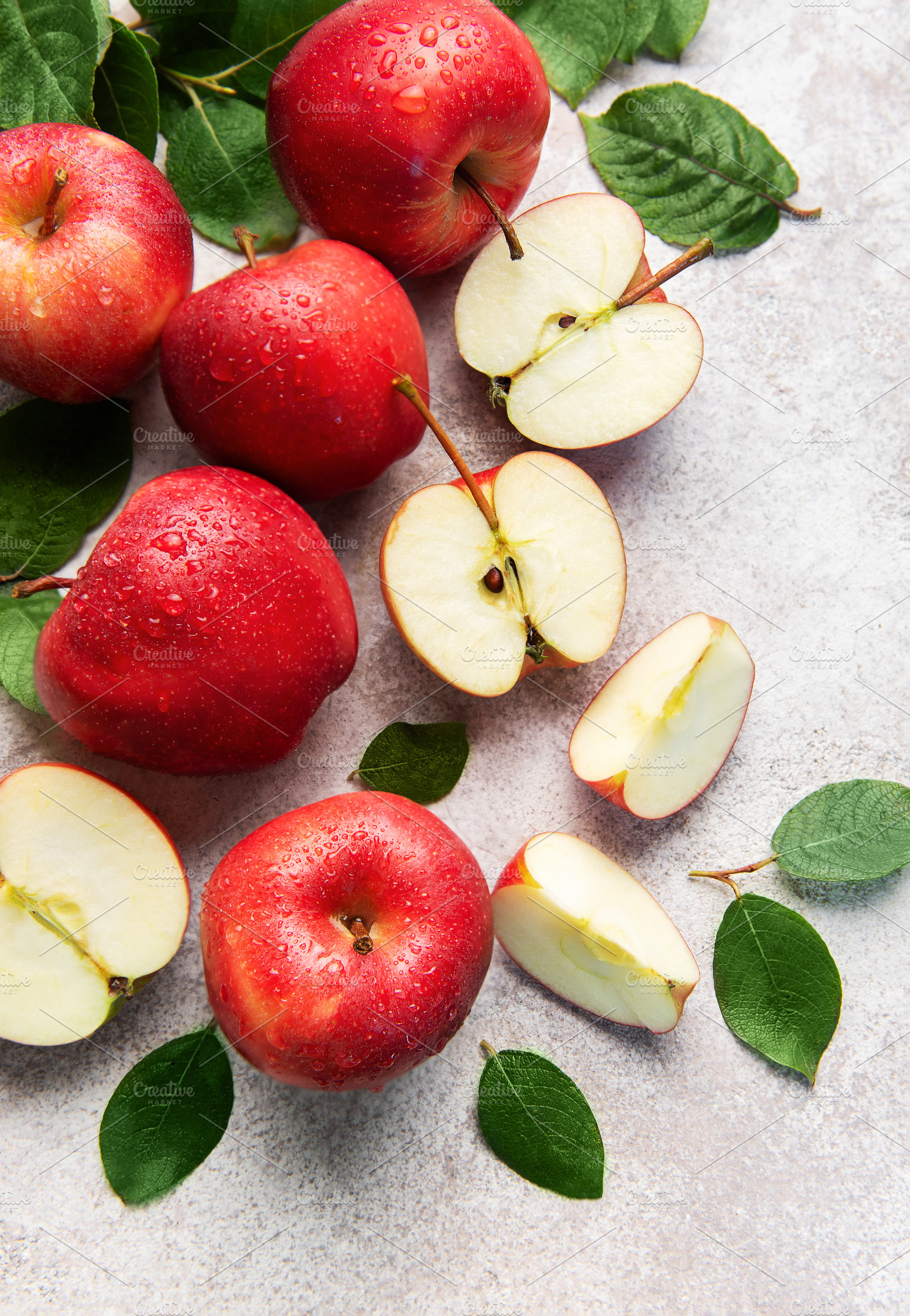 Fresh red apples with green leaves on grey background, a Food & Drink Photo by Olena Rudo