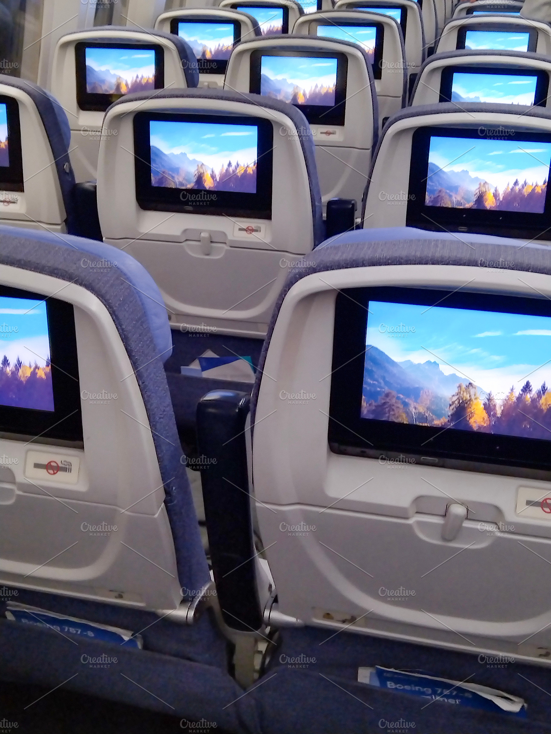 Interior of airplane cabin with personal screens on seats, a Transportation Photo by DanFLCreativo
