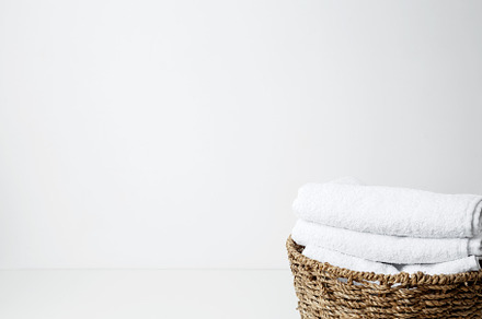 Basket filled with clean white towels in a neat arrangement. Household cleaning