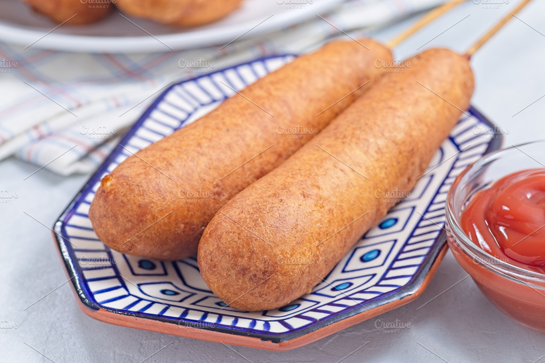 Two corn dogs on white blue plate, served with ketchup, horizontal, a Food & Drink Photo by iuliia_n
