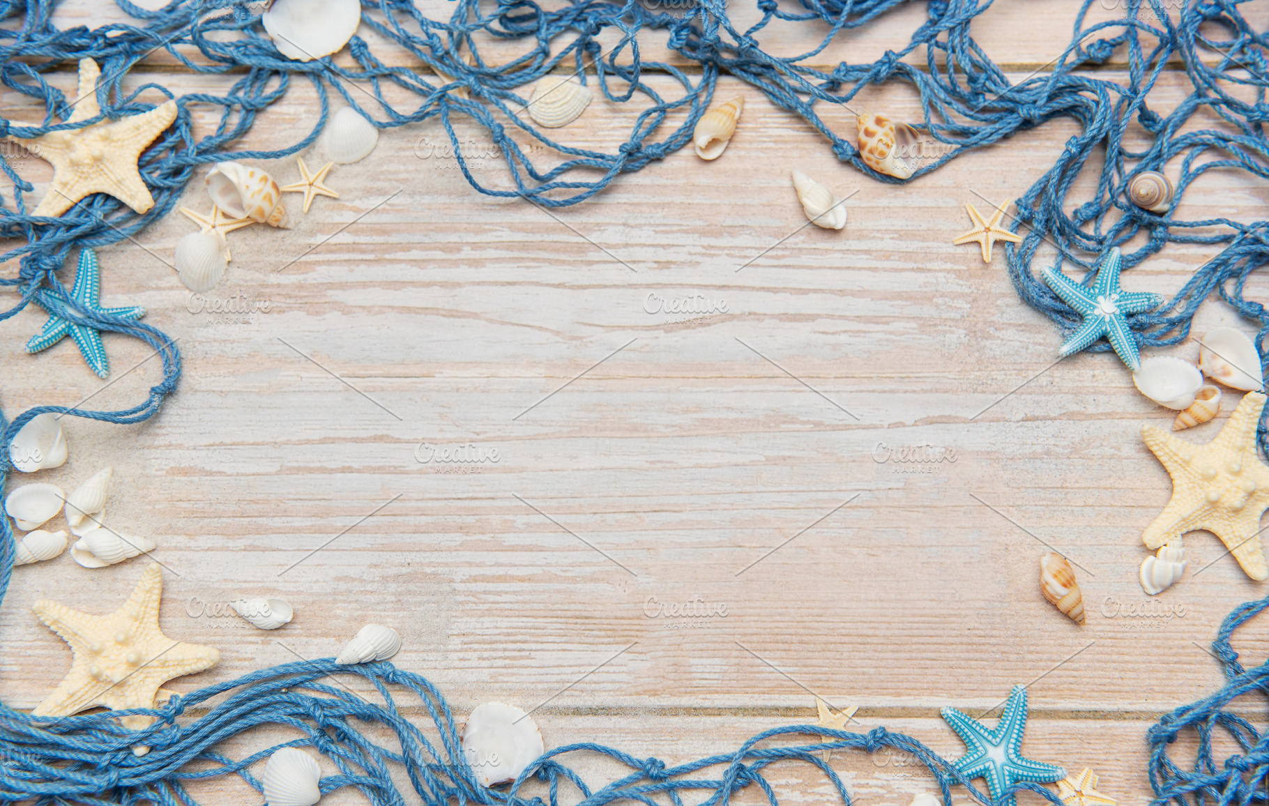 Fishing net, starfishes and seashells framing rustic wooden back, a Holiday Photo by Olena Rudo