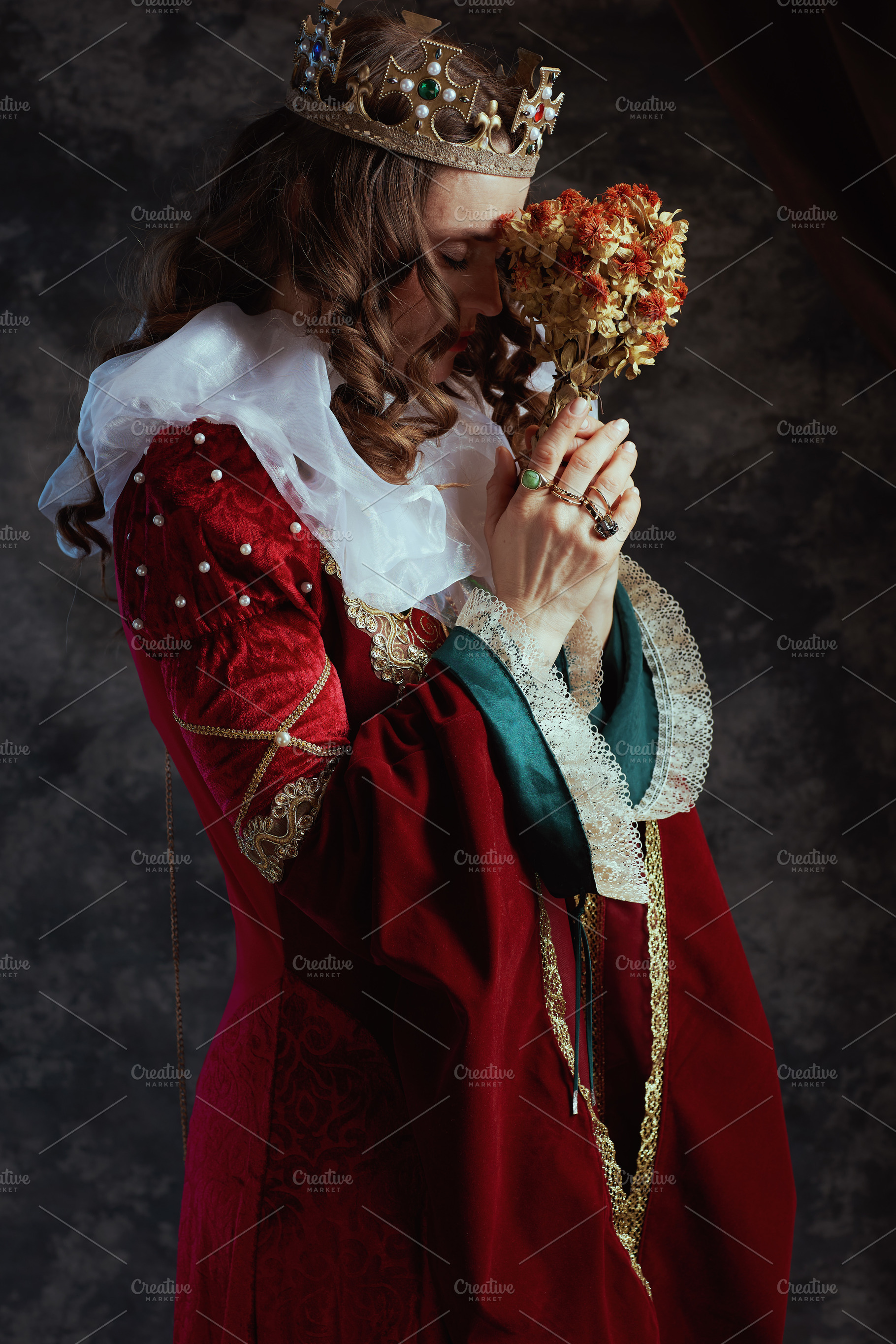 stressed medieval queen in red dress with dried flower, a Person Photo by Alliance Images