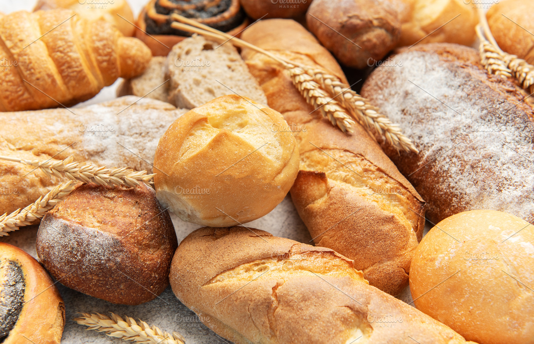 Variety of fresh baked bread, pastry, and wheat ears, a Food & Drink Photo by Olena Rudo