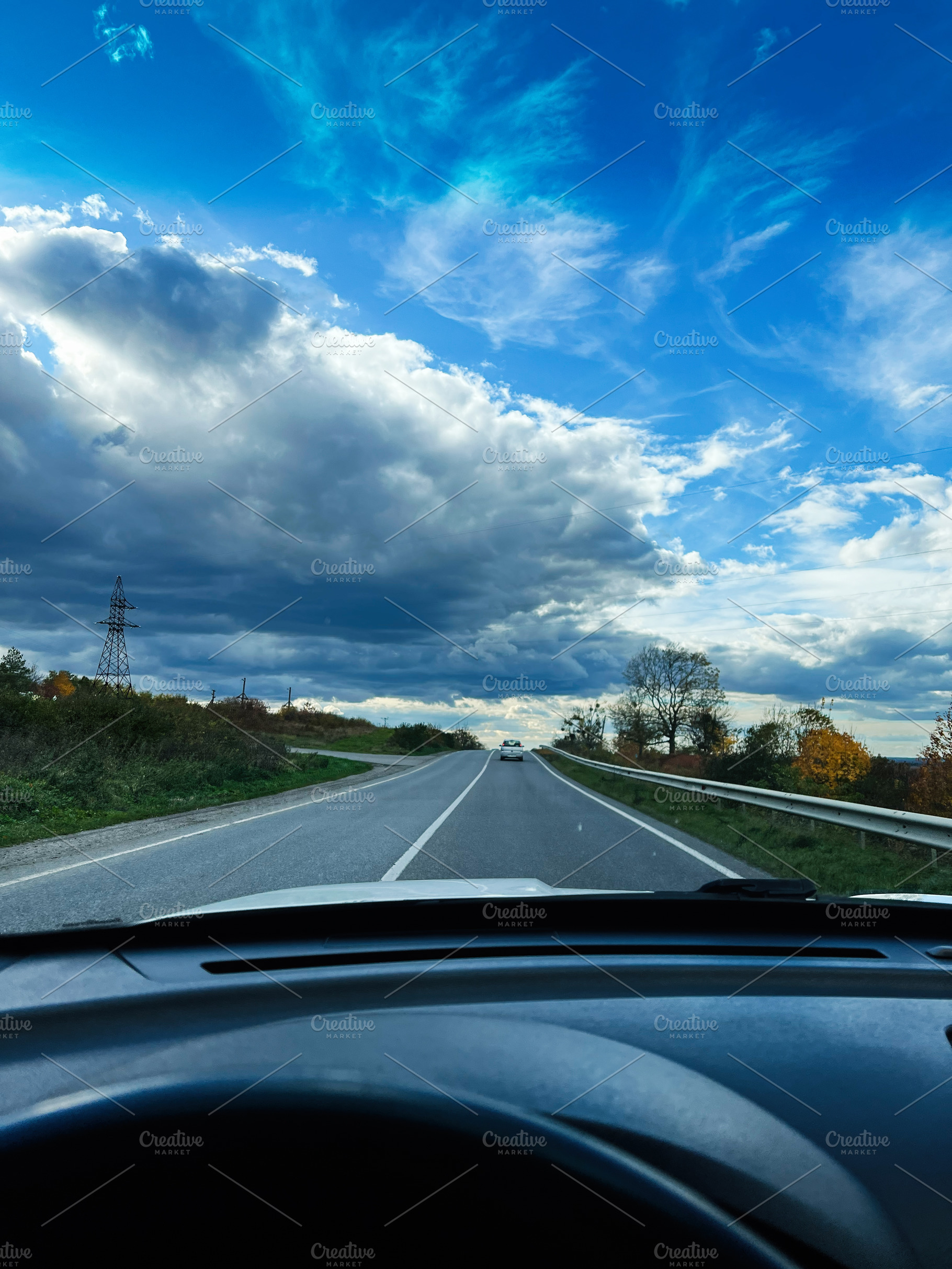 Open road ahead under dramatic blue sky with clouds, viewed from car interior, a Photo by AS photostudio