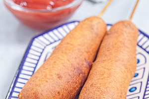 Two corn dogs on white blue plate, served with ketchup, vertical, a Food & Drink Photo by iuliia_n