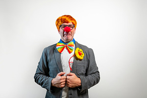 Clown experiencing sadness and crying wearing a business suit, a Person Photo by karrastock