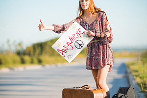 Lovely young hippie girl hitchhiking