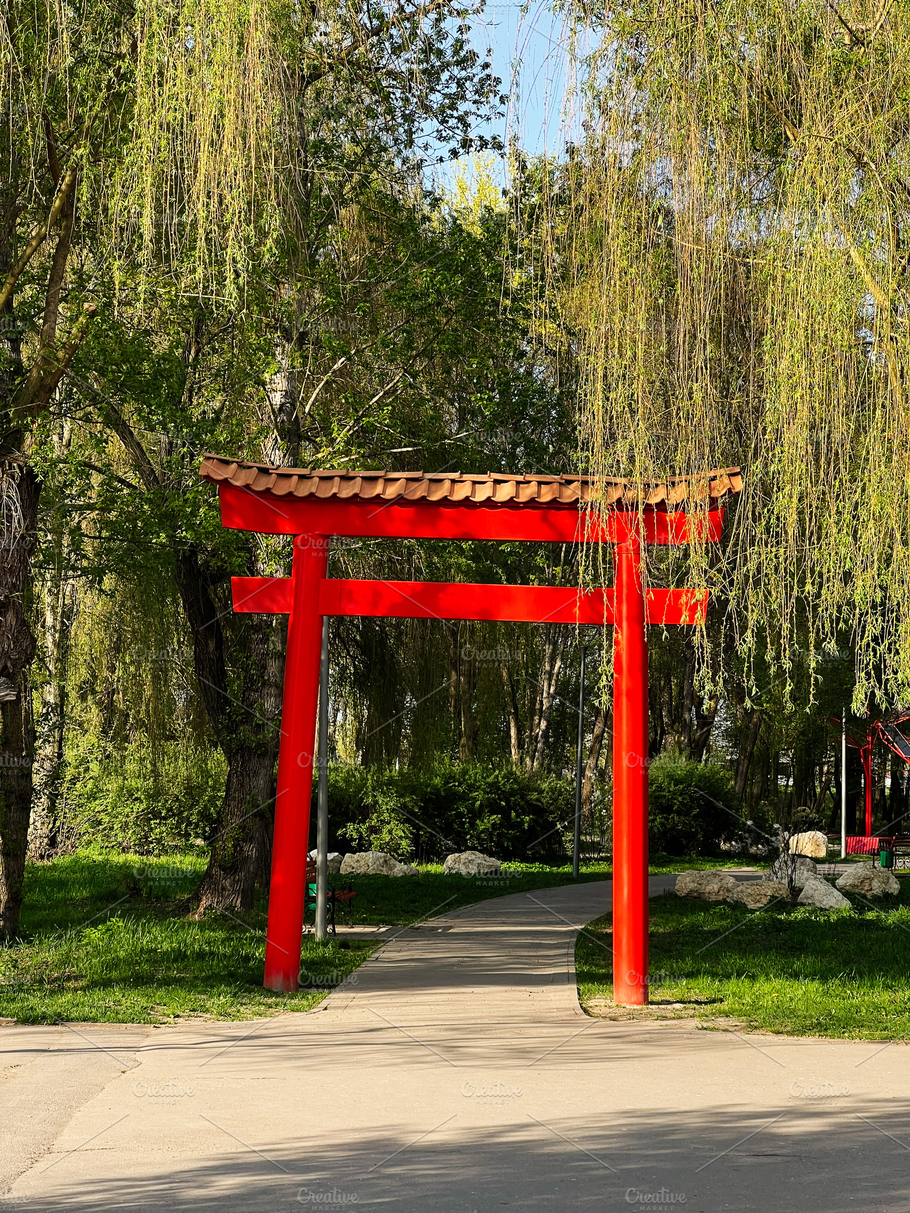 Red Torii gate surrounded by lush green trees on a bright sunny day, a Photo by AS photostudio