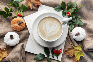 Warm autumn coffee with latte art and pumpkins