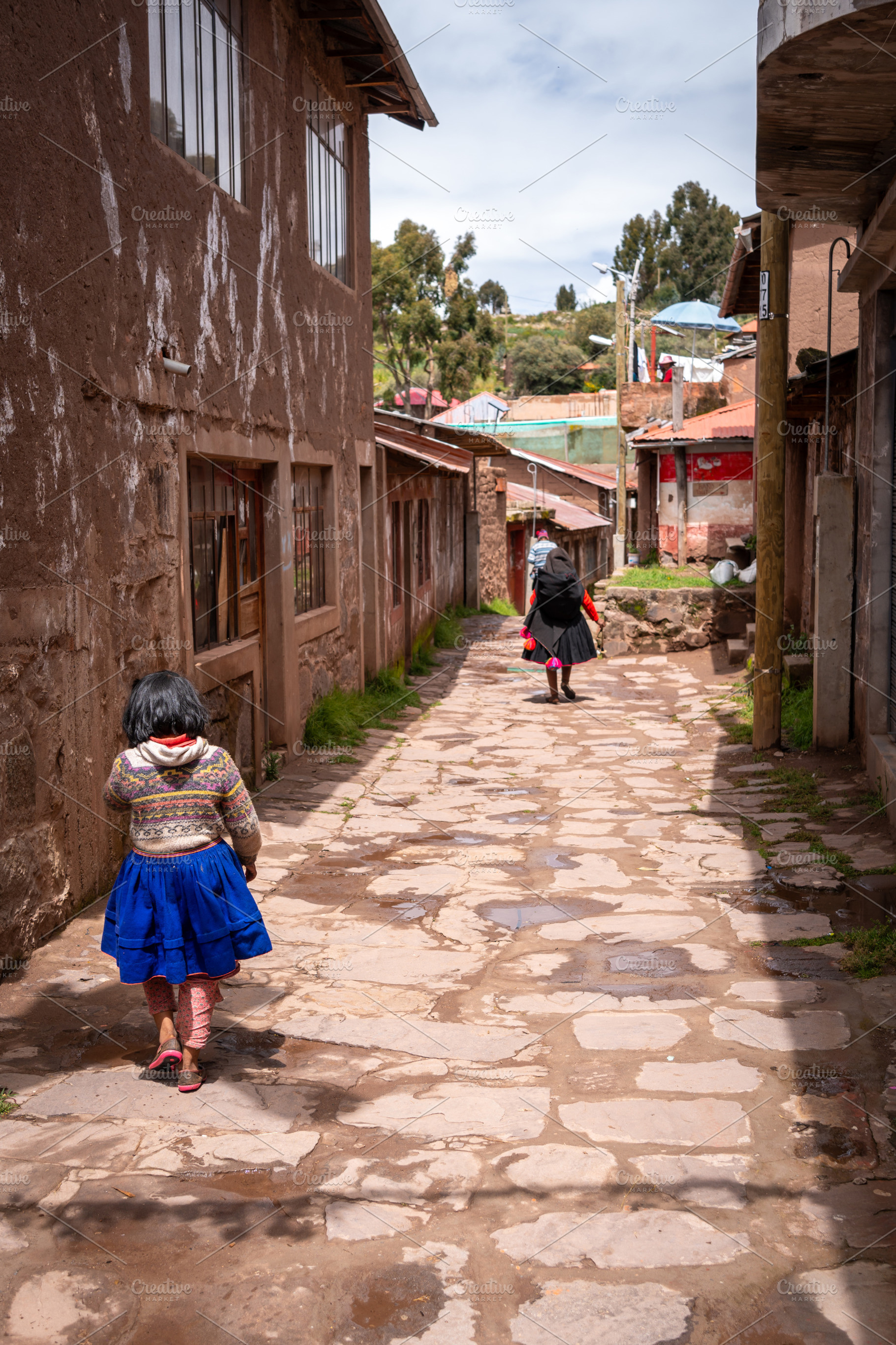 Andean girl and woman walking in a village on Taquile Island, an Architecture Photo by GoodGoods
