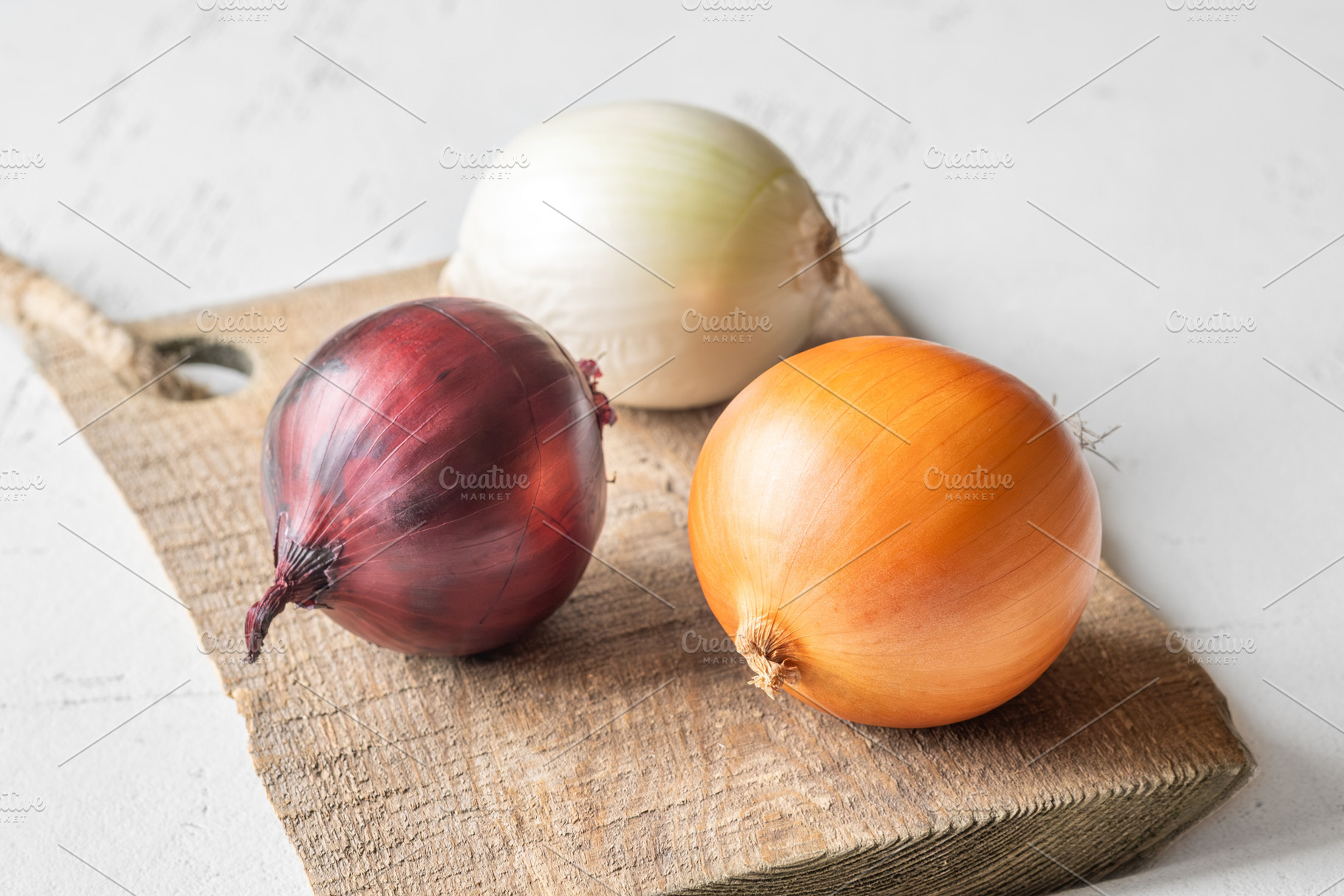Three whole onions on rustic board, a Food & Drink Photo by Alexander Prokopenko