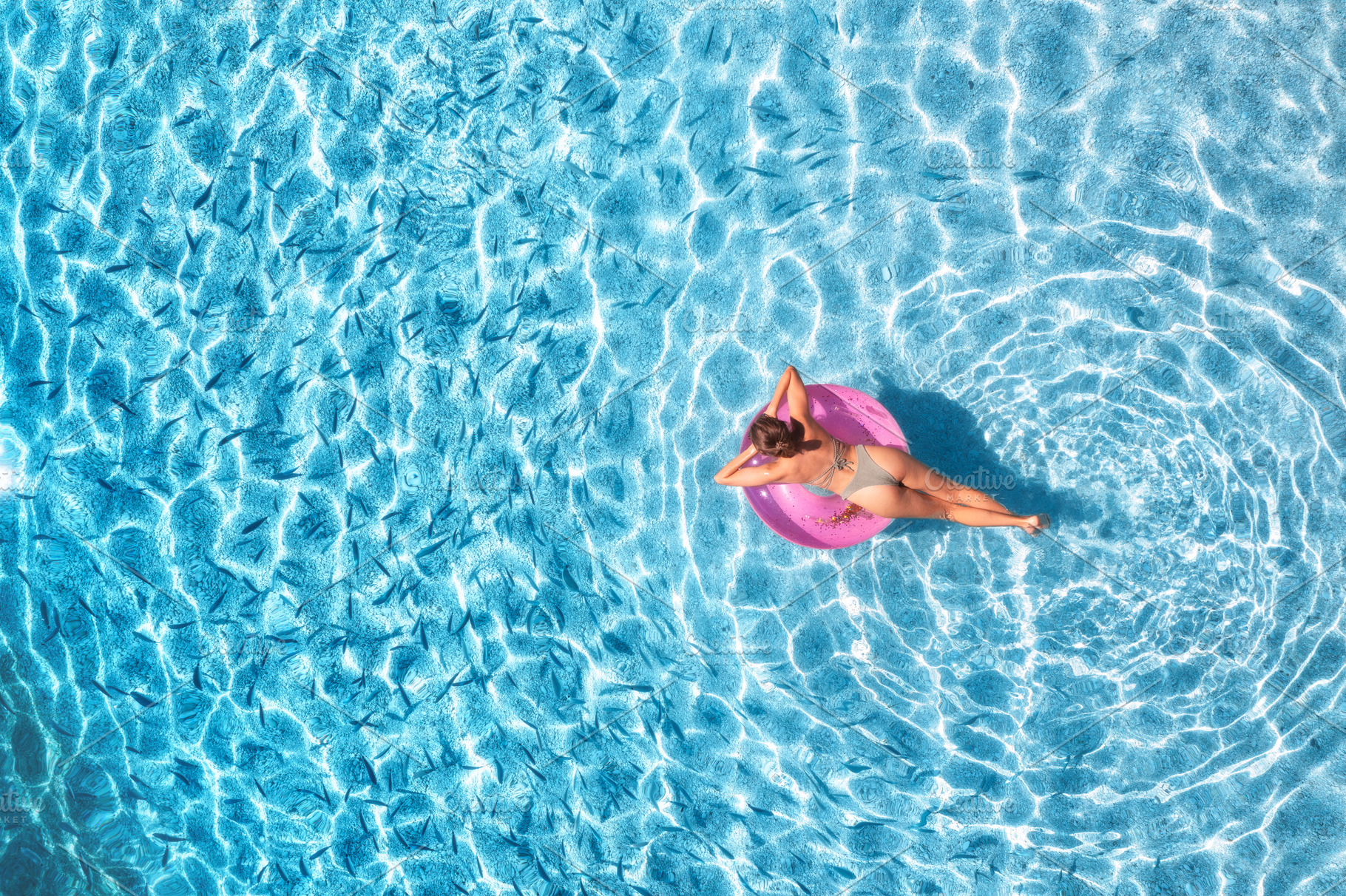 Aerial view of a young woman in hat swimming with pink swim ring, a Holiday Photo by den-belitsky