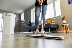 Woman mopping, wiping floor in home setting. Housewife uses mop, plastic bucket, a Person Photo by Lenor4ik