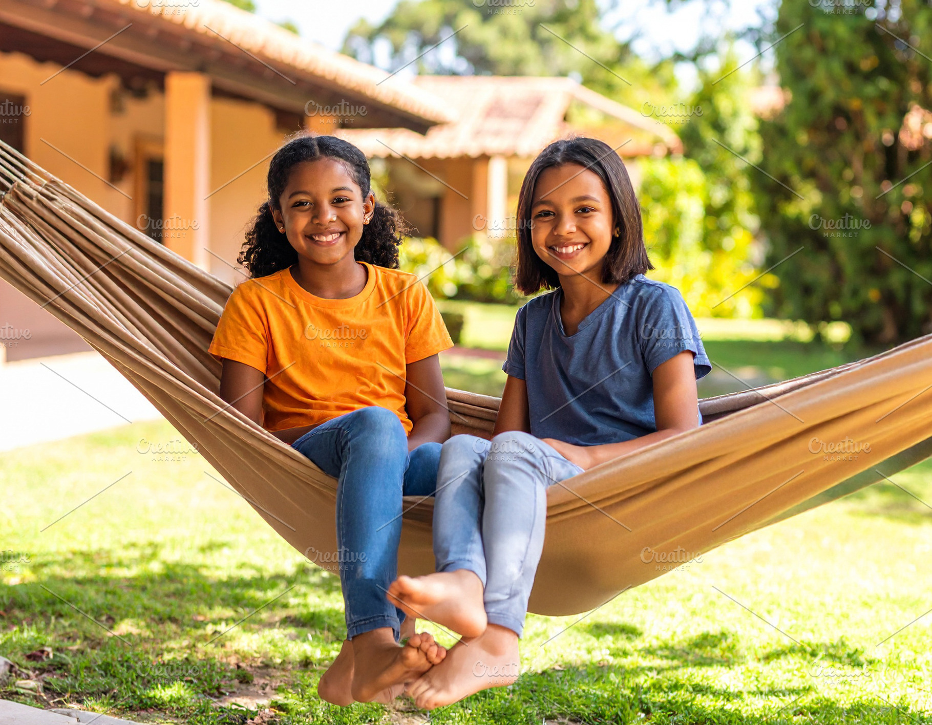 Two girls sitting together on a hammock in the backyard of a hou, a Person Photo by DanFLCreativo