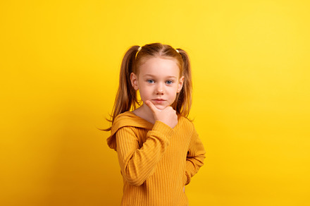 Young girl in a mustard sweater posing with a thoughtful express