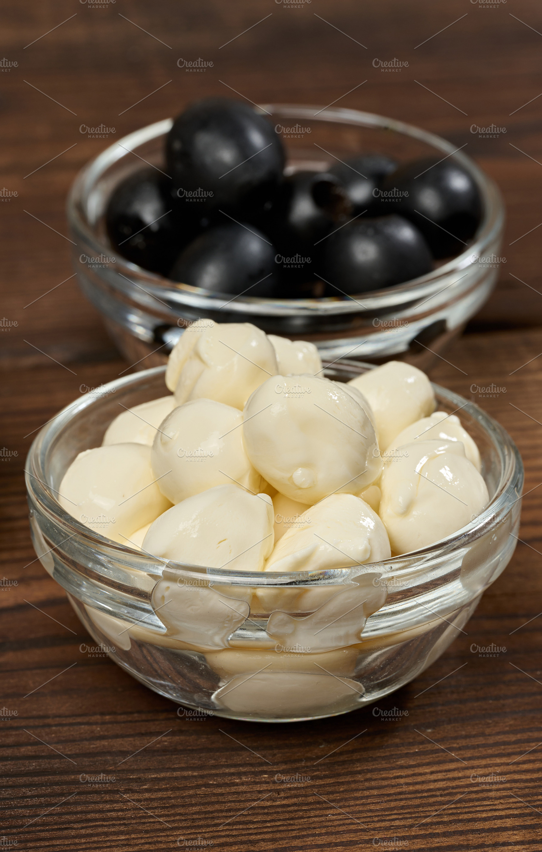 Mozzarella balls in a glass bowl in the foreground, blurred oliv, a Food & Drink Photo by ndanko