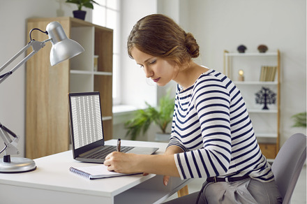 Left-handed woman makes notes in her, a Business Photo by StudioRomantic