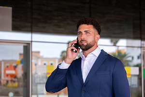 Businessman talking on smartphone outside office, a Business Photo by etorres69