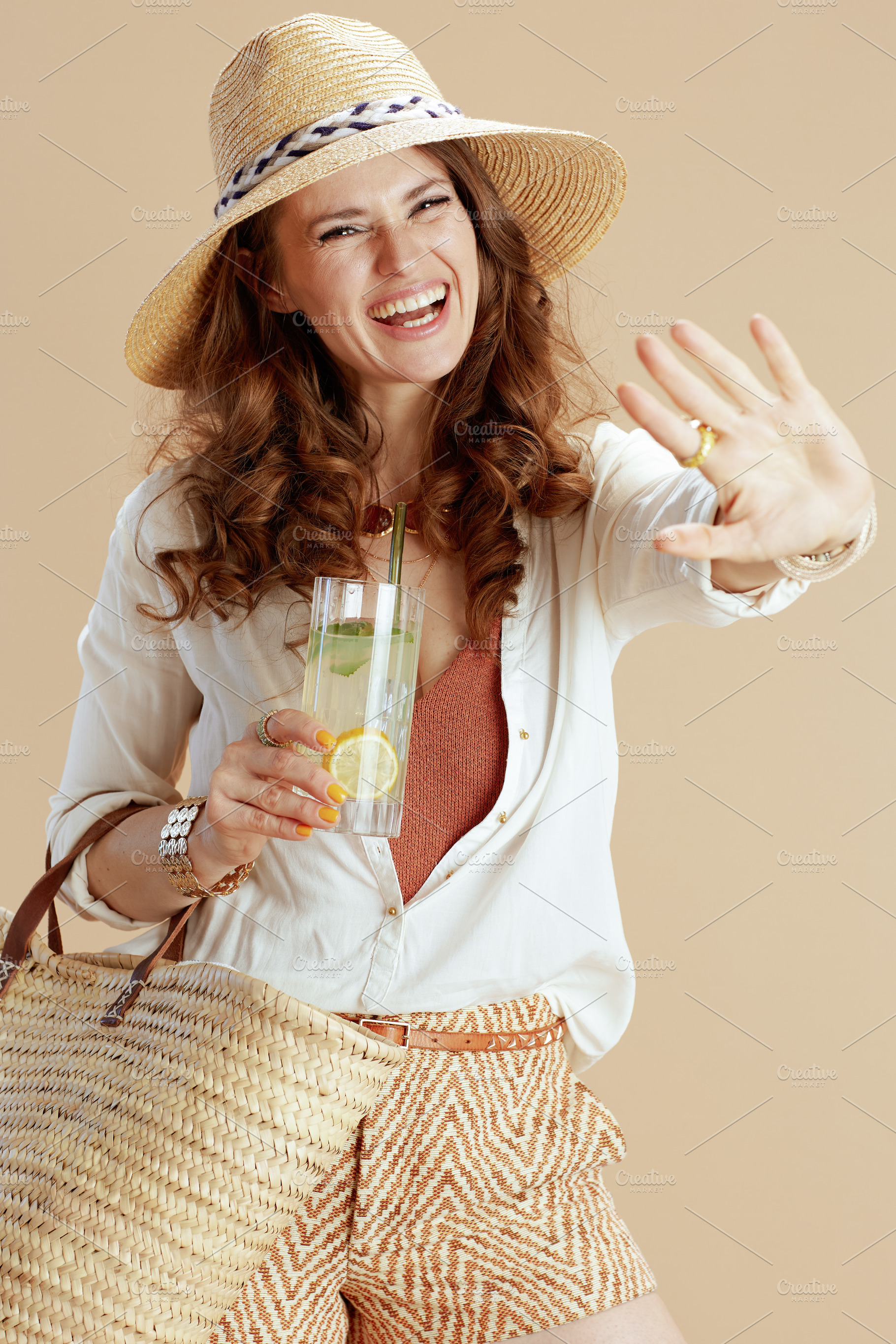 smiling woman in blouse and shorts against beige, a Person Photo by Alliance Images