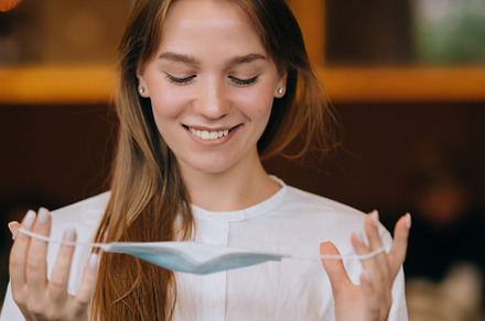 Girl in takes off her protective medical face mask