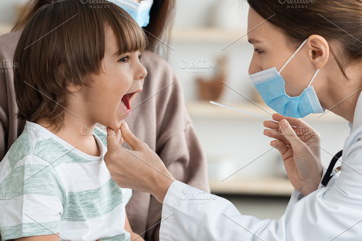 Professional woman pediatrician wearing protective face mask checking throat of, a Photo by Prostock-Studio (Photo 2 of 2)