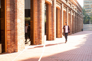 Young man walking through brick corridor in sunlight, a Person Photo by RF Images