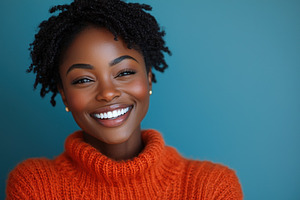 Joyful woman in orange sweater laughing with eyes closed against a blue backgro, a Person Photo by José Manuel Gelpi