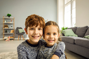 Two children smiling at camera on sofa, a Person Photo by DanFLCreativo