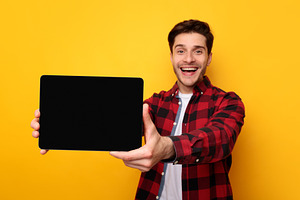 Happy young man showing black empty tablet screen