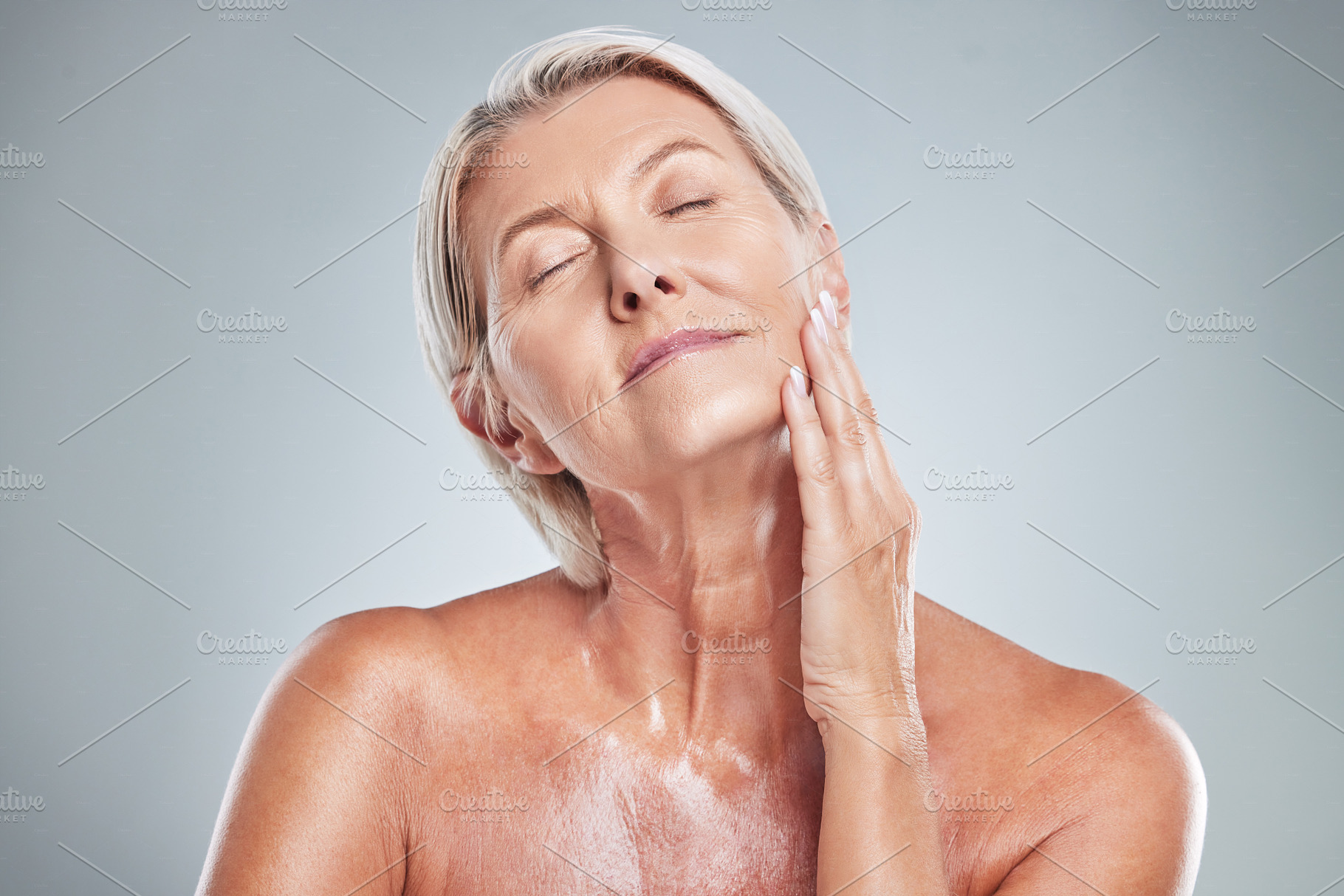 Senior woman, relax and skincare beauty for cosmetics, moisturizer or treatment against a grey studio background. Elderly female hand touching face in satisfaction for perfect skin or facial care, a Photo by Peopleimages.com