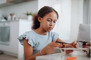 Focused girl working on small robot, a School & Education Photo by HalfPoint