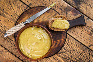 Sweet pistachio cream spread on bread with wooden bowl and knife, a Food & Drink Photo by composter-box@mail.ru