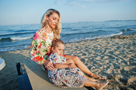 Mother and beautiful daughter having fun on the beach, sitting o, a Person Photo by AS photostudio