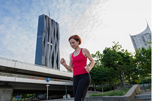 sporty woman running across a city, a Person Photo by HalfPoint