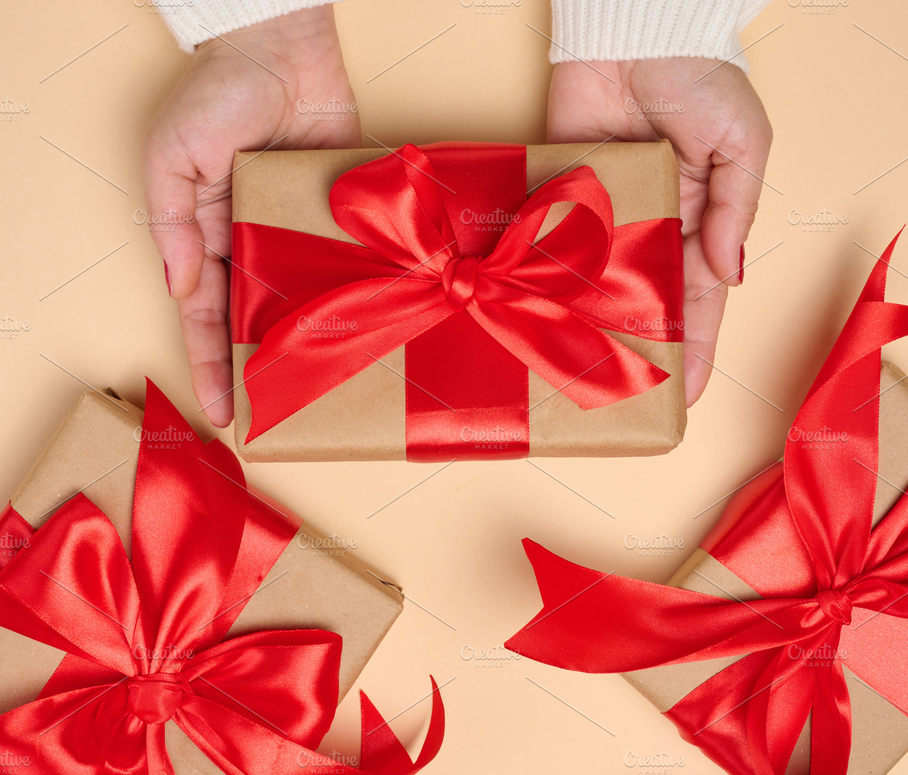 A woman's hands in a white sweater hold a gift box wrapped in cr, a Holiday Photo by ndanko