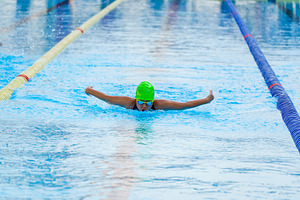 Swimmer child swims butterfly swimming style in a race swimming
