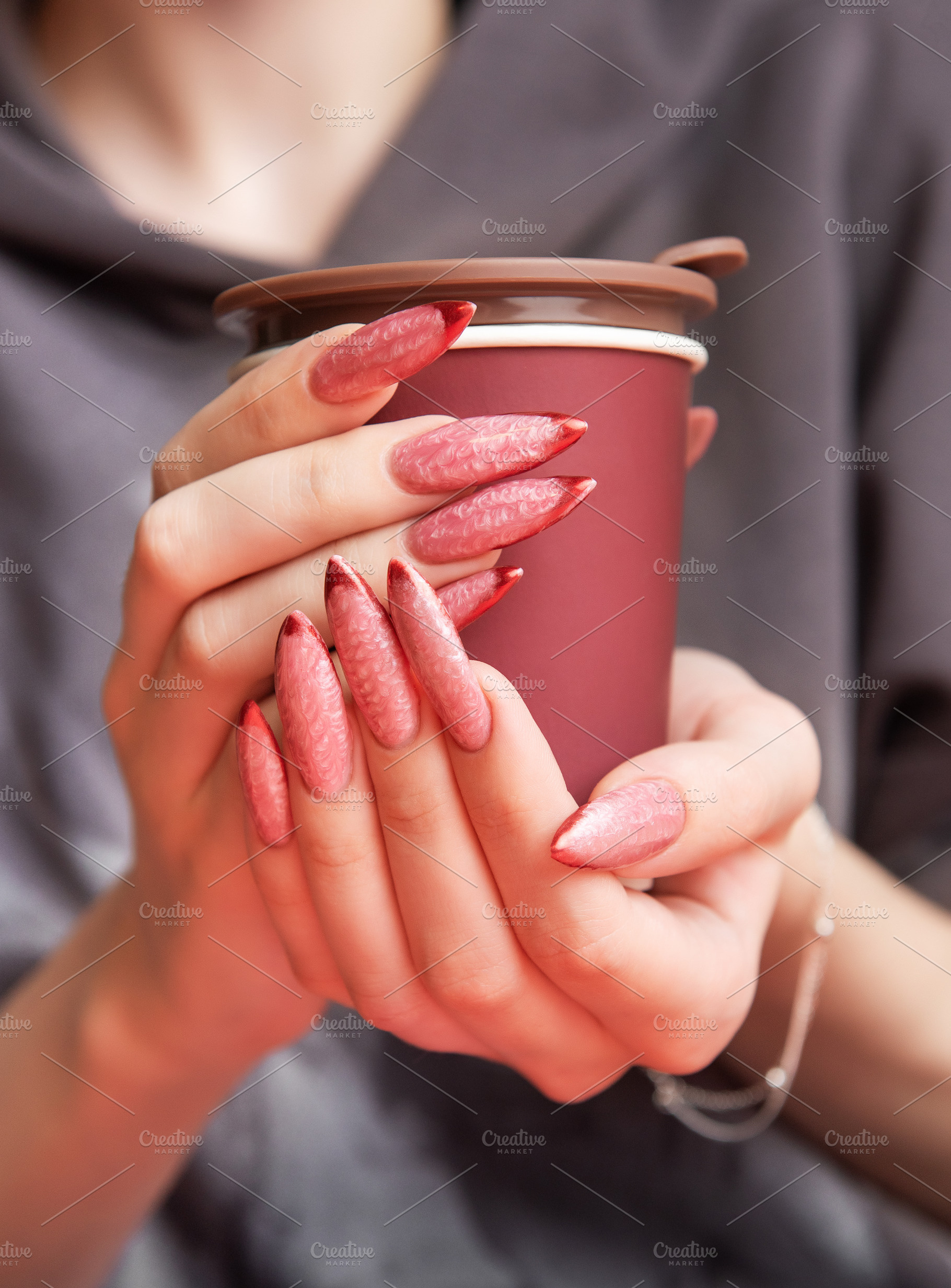 Woman holding insulated cup with long red ombre manicure, a Beauty & Fashion Photo by Olena Rudo