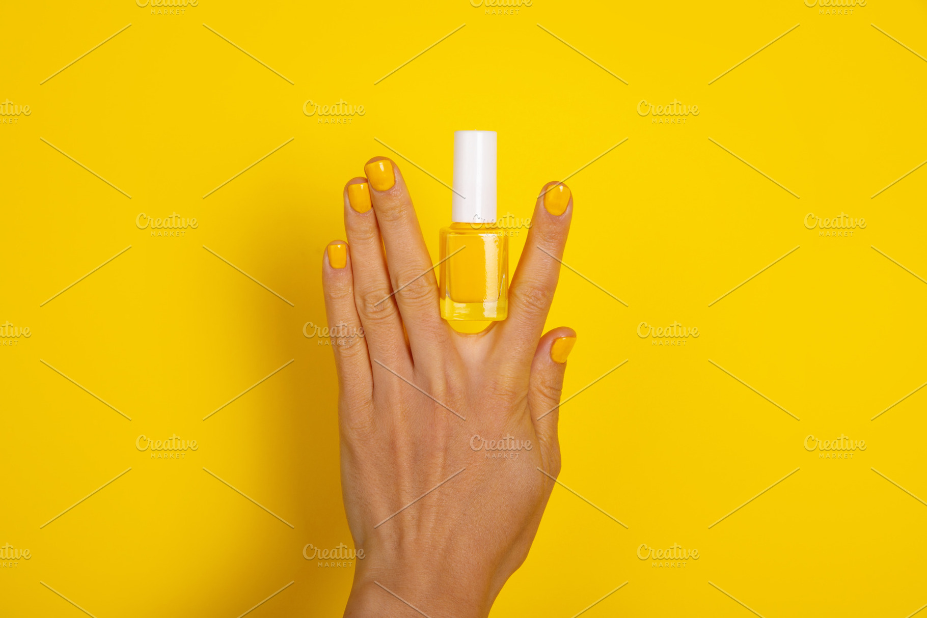 Female hand with yellow polished nails holding a yellow nail pol, a Beauty & Fashion Photo by Ales Munt
