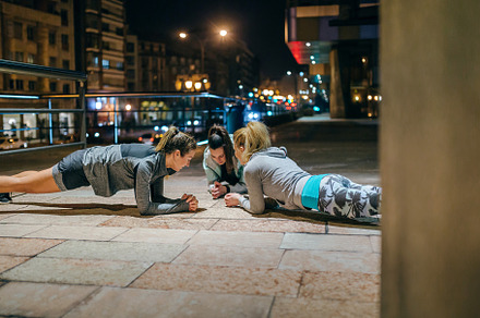 Women sport team doing plank exercise during training on the cit