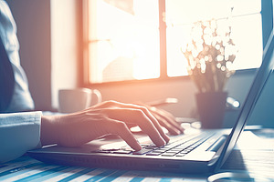 Close-up of hands typing on a laptop in a modern office setting, an Illustration by AS photostudio