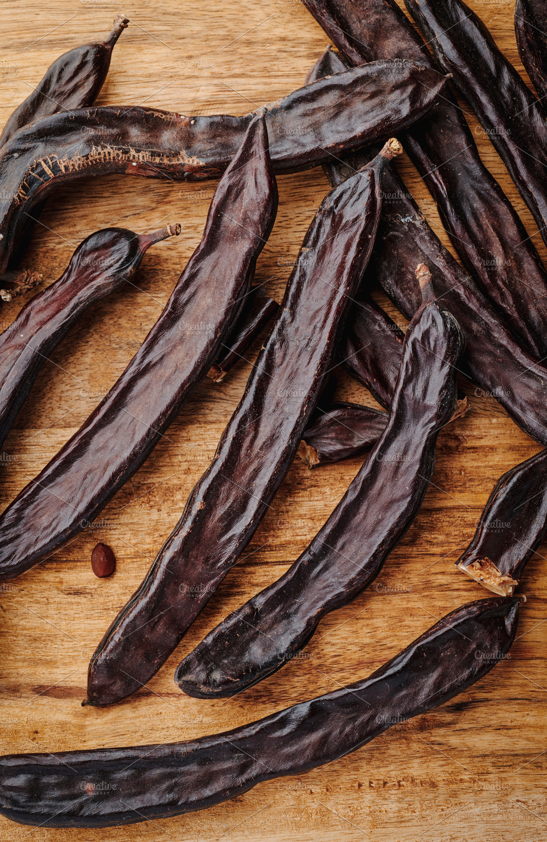 closeup of some ripe carob pods on a table, a Photo by Nito