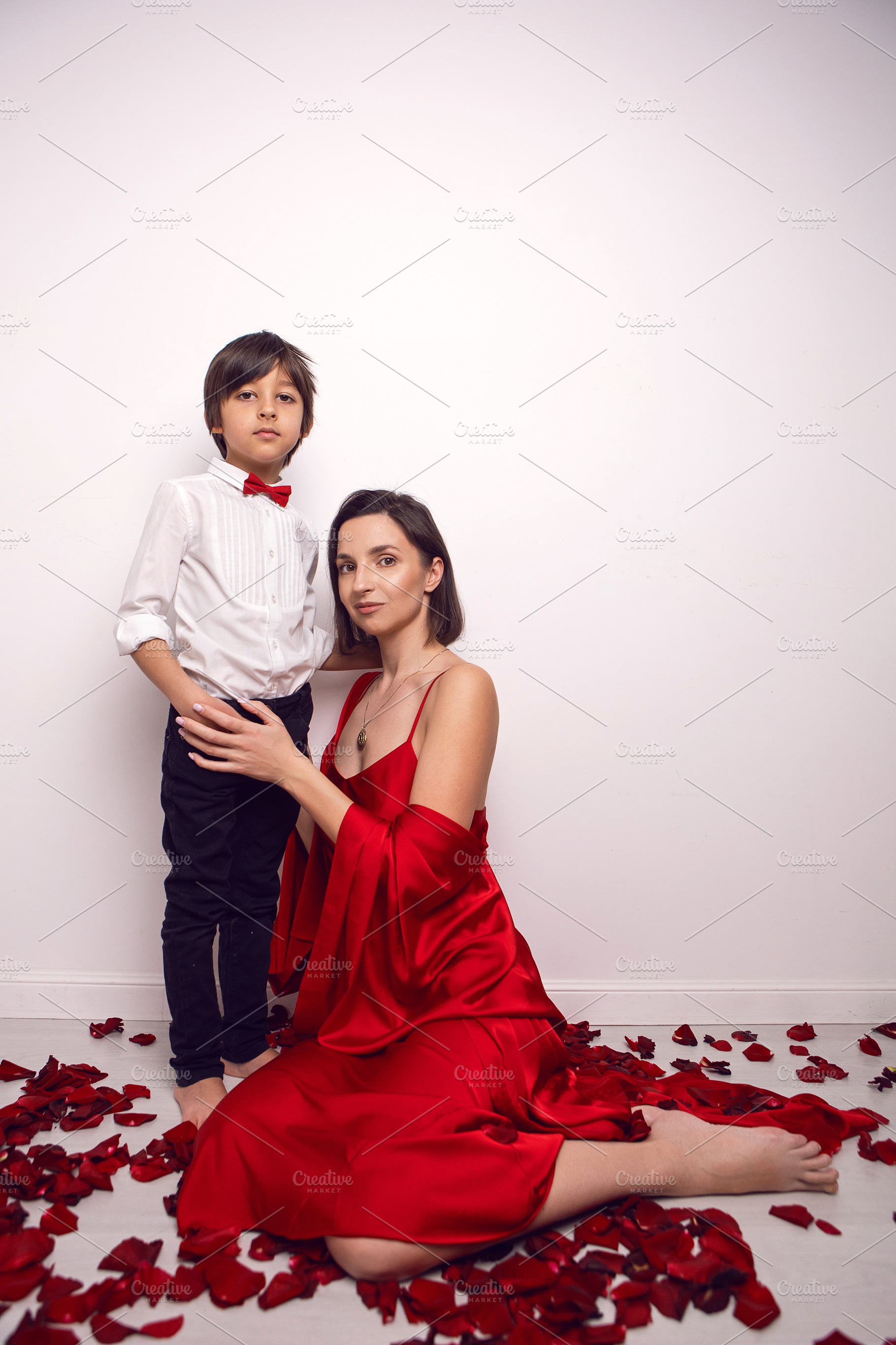 mother in a red dress is sitting on the floor with a child, a six-year-old son, a Person Photo by SaulichPhoto