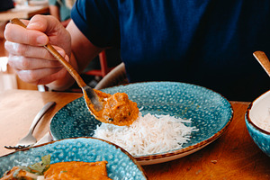 a man adding tikka masala to his rice, a Photo by Nito